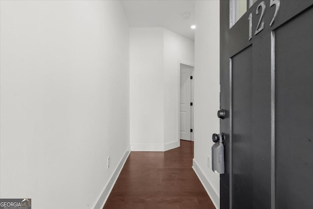corridor featuring baseboards and dark wood-style floors