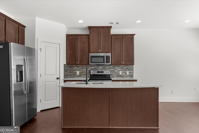 kitchen featuring stainless steel appliances, light countertops, visible vents, a sink, and decorative backsplash