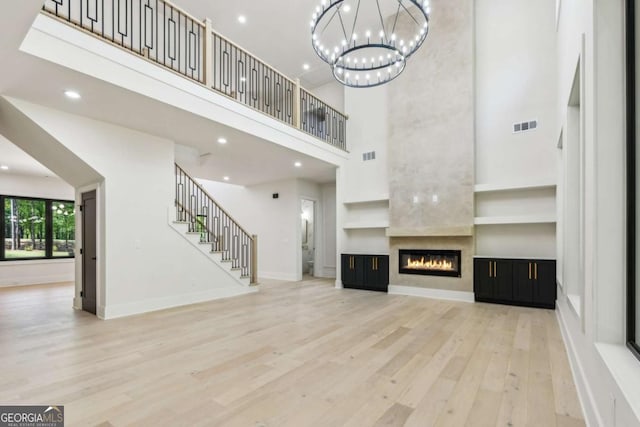 2205 Sugarloaf Pkwy, Lawrenceville, GA 30045 - unfurnished living room featuring a towering ceiling, wood finished floors, stairs, recessed lighting, and a large fireplace