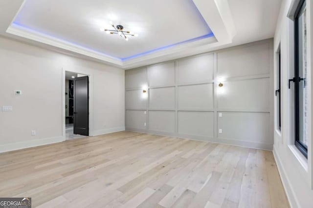 2205 Sugarloaf Pkwy, Lawrenceville, GA 30045 - empty room featuring a tray ceiling, light wood-type flooring, and a decorative wall