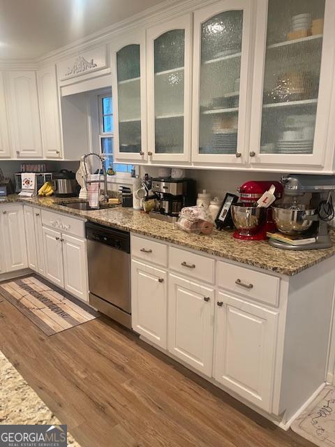 kitchen with stainless steel dishwasher, white cabinetry, and a sink