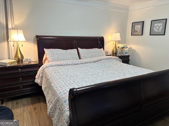 bedroom featuring ornamental molding and wood finished floors