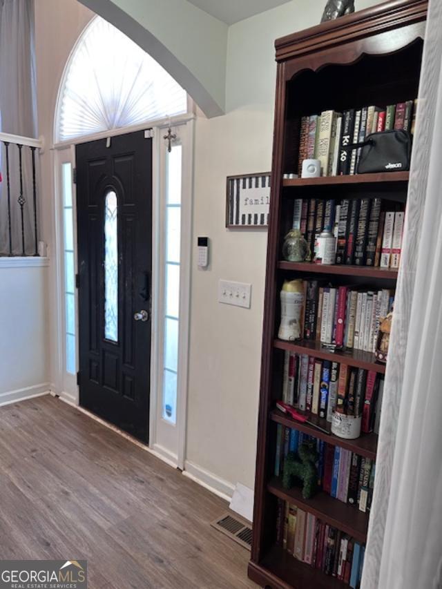 foyer entrance with baseboards, wood finished floors, and arched walkways