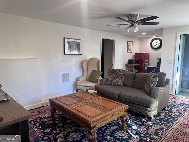 living area with a ceiling fan and baseboards
