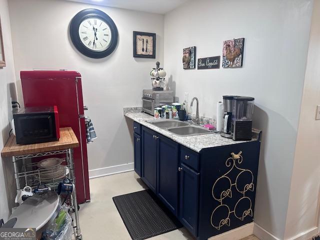 kitchen with blue cabinets, a sink, light countertops, and baseboards