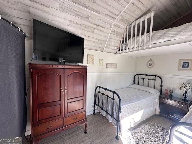 bedroom featuring wainscoting, wooden ceiling, wood finished floors, and vaulted ceiling