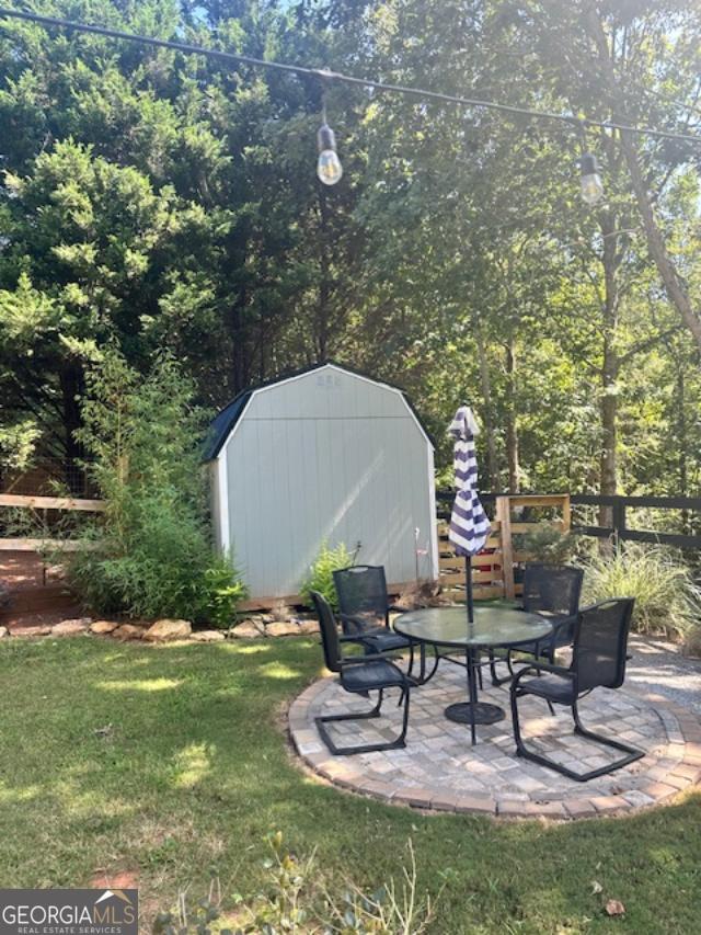 view of yard featuring a storage shed, an outdoor structure, and a patio area