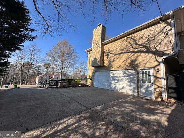 view of side of property with a chimney, a garage, and driveway