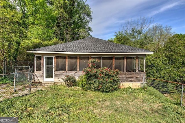 rear view of property featuring a lawn, roof with shingles, a fenced backyard, and a sunroom