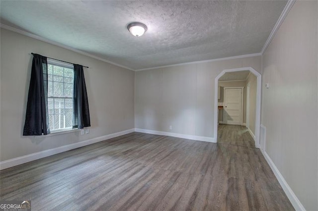 spare room featuring a textured ceiling, visible vents, arched walkways, ornamental molding, and wood finished floors