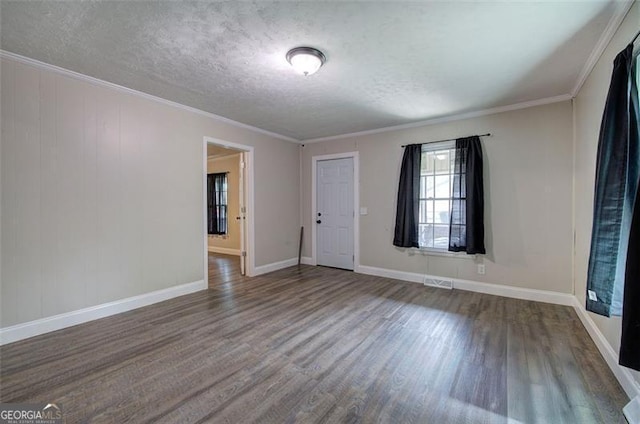 empty room with a textured ceiling, visible vents, wood finished floors, and baseboards