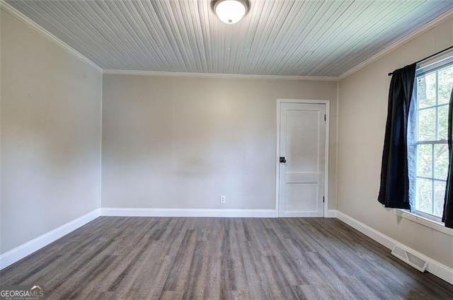 spare room with dark wood-style flooring, visible vents, crown molding, and baseboards