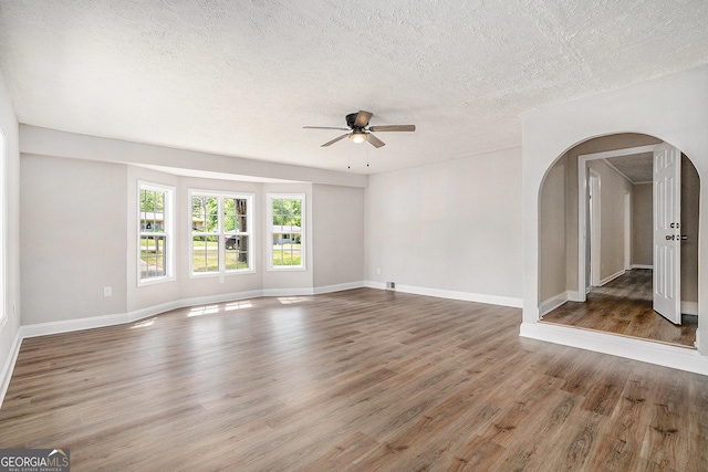 1132 Luther Dr SW, Mableton, GA 30126 - unfurnished living room featuring arched walkways, a ceiling fan, wood finished floors, and a textured ceiling
