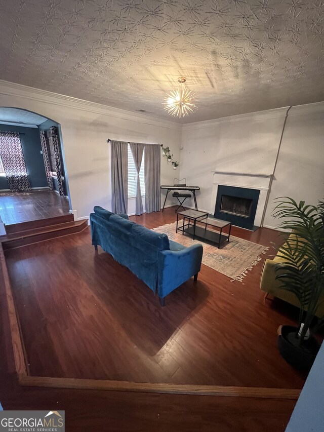 living room with a fireplace with flush hearth, wood finished floors, arched walkways, and crown molding