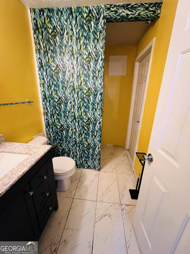 full bath with marble finish floor, toilet, vanity, and curtained shower