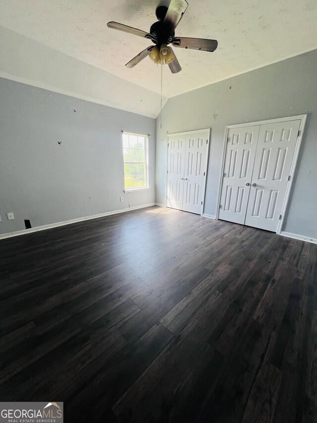 unfurnished bedroom with multiple closets, baseboards, vaulted ceiling, and dark wood finished floors