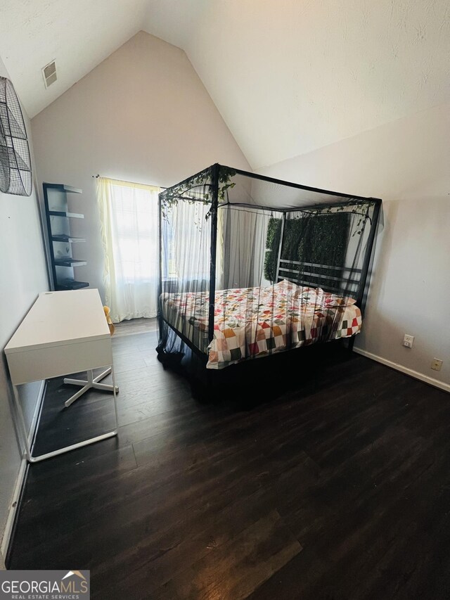bedroom with vaulted ceiling, wood finished floors, visible vents, and baseboards