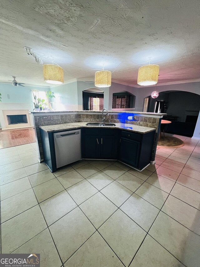 kitchen with dark cabinets, dishwasher, a sink, light tile patterned flooring, and open floor plan
