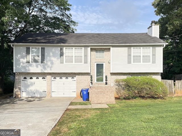 raised ranch with brick siding, driveway, a chimney, and a garage