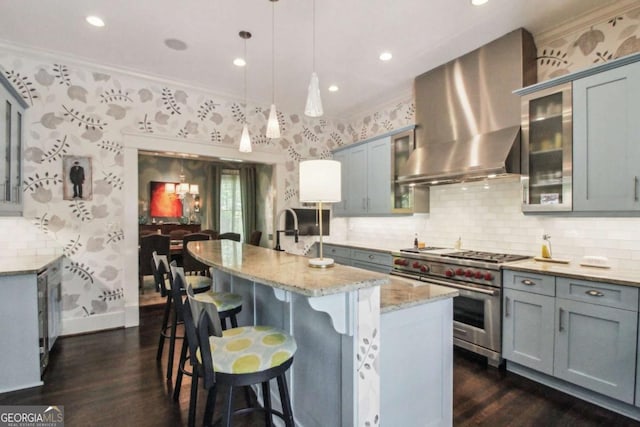 kitchen with ornamental molding, high end range, wall chimney exhaust hood, and dark wood-style flooring