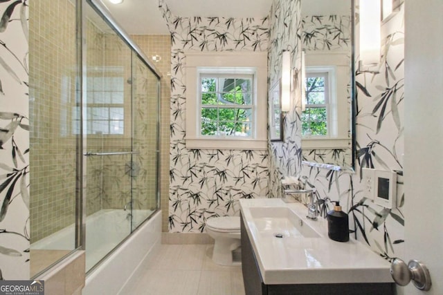 bathroom with shower / bath combination with glass door, toilet, vanity, and tile patterned floors