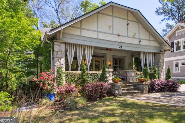 view of front facade featuring stone siding, ceiling fan, and covered porch