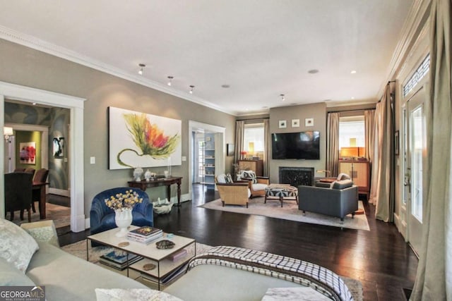 living room featuring baseboards, wood finished floors, a wealth of natural light, and crown molding