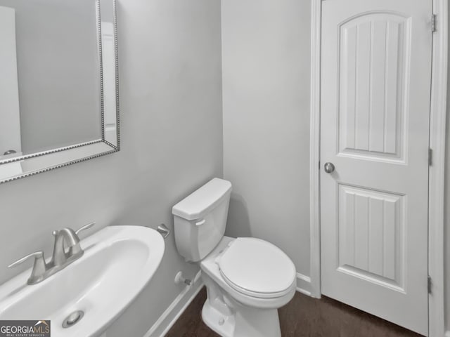 2470 Bridle Bridge Trl, Cumming, GA 30040 - half bathroom featuring wood finished floors, baseboards, a sink, and toilet
