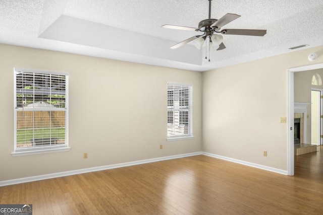 unfurnished room featuring a textured ceiling, visible vents, baseboards, a ceiling fan, and wood finished floors