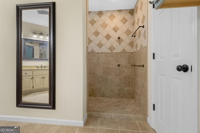 bathroom featuring a tile shower, baseboards, vanity, and tile patterned floors