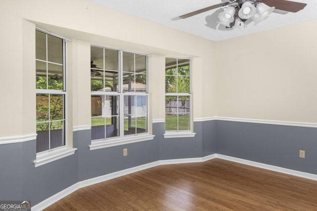 empty room featuring ceiling fan, baseboards, and wood finished floors
