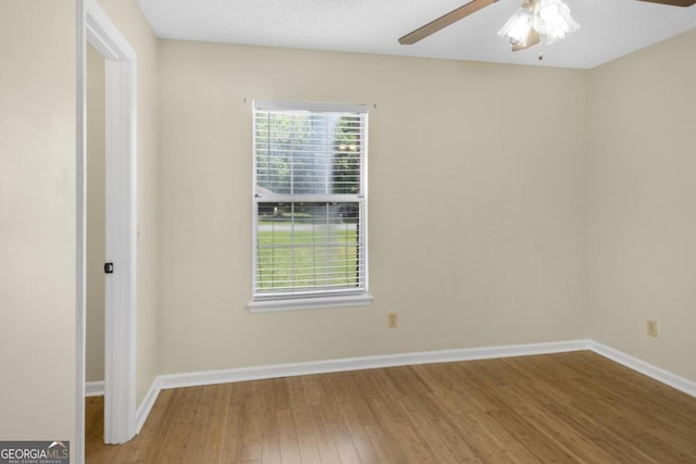 spare room with wood finished floors, a ceiling fan, and baseboards