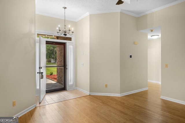 foyer entrance with baseboards, crown molding, wood finished floors, and ceiling fan with notable chandelier