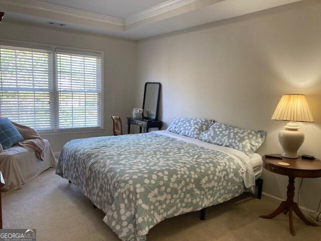 carpeted bedroom featuring crown molding, visible vents, a raised ceiling, and baseboards