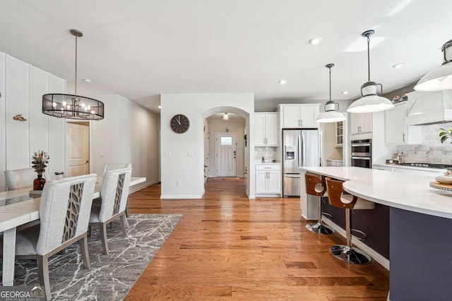 2815 Paddle Point Ln, Cumming, GA 30041 - kitchen with stainless steel appliances, light countertops, arched walkways, and tasteful backsplash