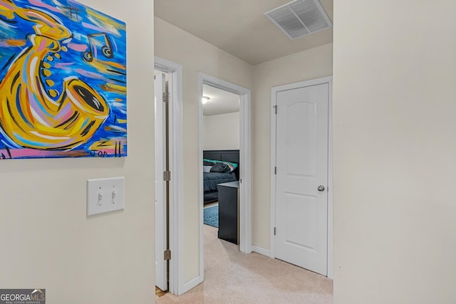 hall with carpet floors, baseboards, and visible vents