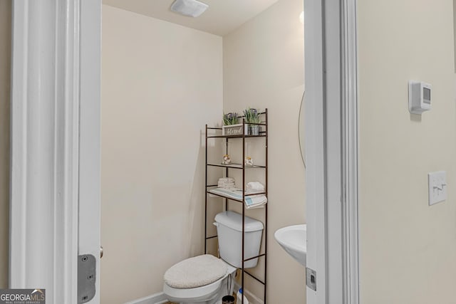 half bath with baseboards and toilet