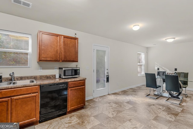 kitchen featuring brown cabinetry, visible vents, dishwasher, a sink, and stainless steel microwave