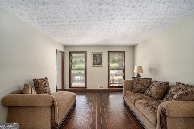living area featuring baseboards, dark wood-style flooring, and a textured ceiling