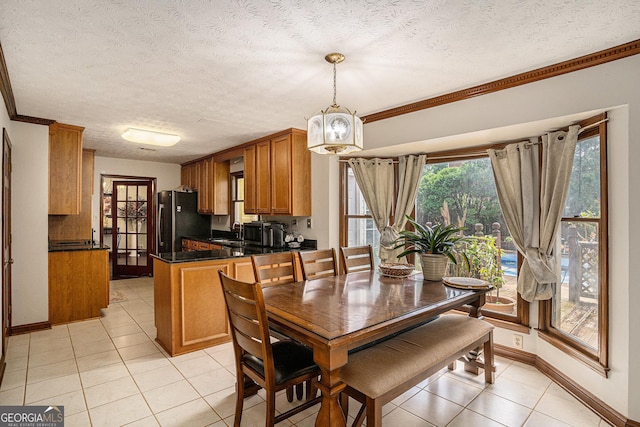 dining space with light tile patterned floors, crown molding, baseboards, and a textured ceiling
