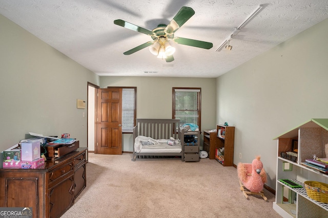 bedroom with carpet, a textured ceiling, and a ceiling fan