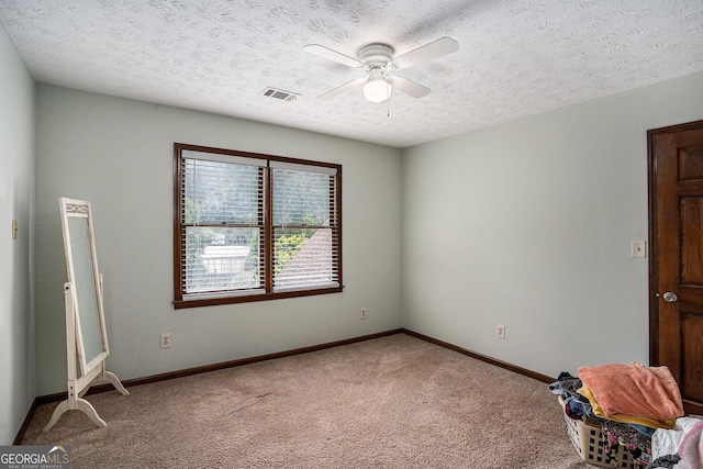 unfurnished bedroom with light carpet, a textured ceiling, baseboards, and a ceiling fan