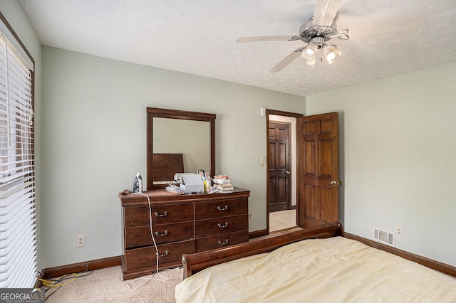 carpeted bedroom featuring baseboards, a ceiling fan, and a textured ceiling