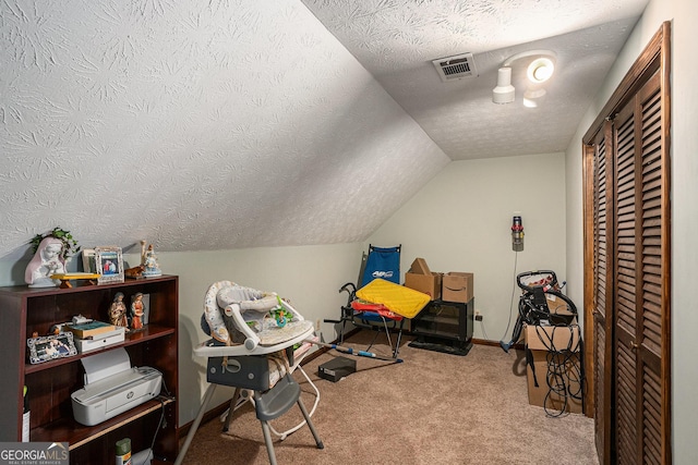 recreation room featuring a textured ceiling, carpet floors, vaulted ceiling, and baseboards