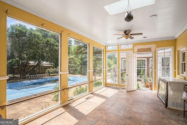 unfurnished sunroom featuring a skylight, ceiling fan, healthy amount of natural light, and crown molding
