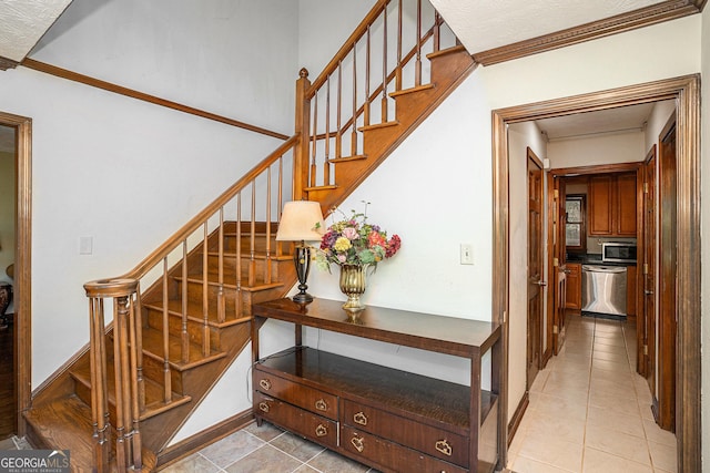 stairway featuring crown molding and tile patterned flooring