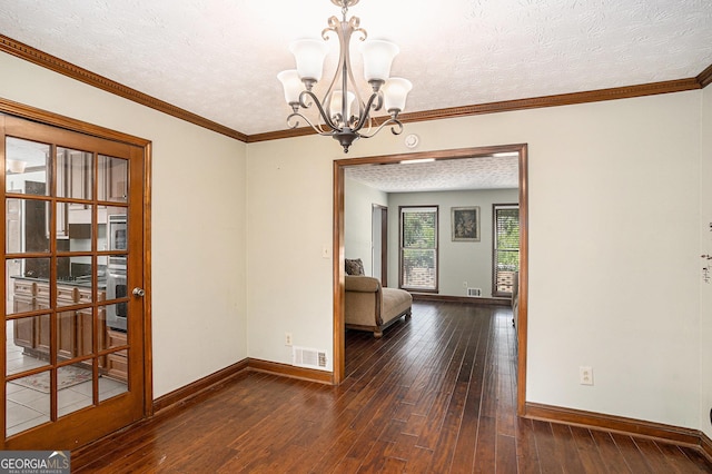 empty room featuring a chandelier, wood-type flooring, baseboards, a textured ceiling, and crown molding