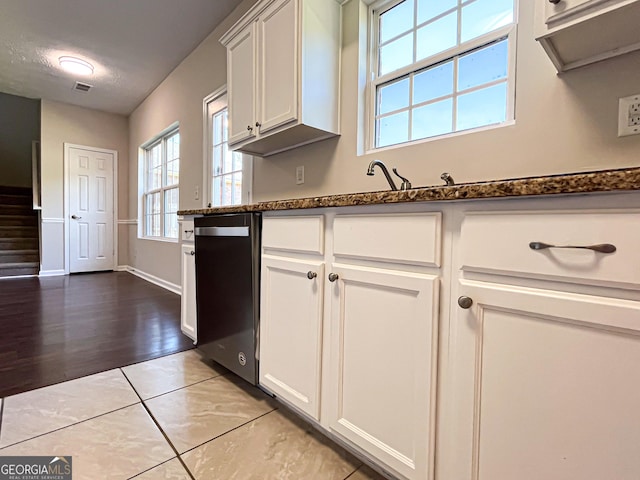 417 Bell Flower Trl, Locust Grove, GA 30248 - kitchen with dark stone countertops, light tile patterned flooring, dishwasher, baseboards, and white cabinetry