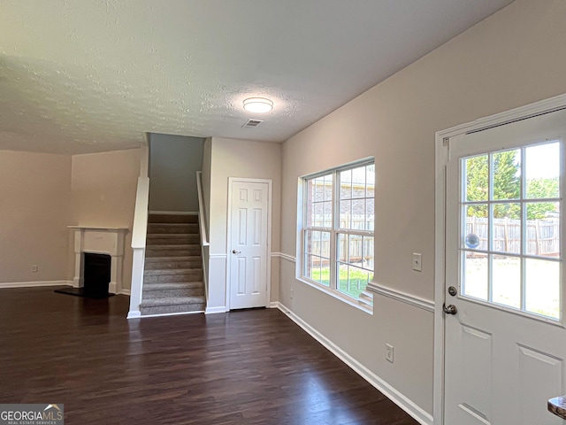 417 Bell Flower Trl, Locust Grove, GA 30248 - doorway to outside featuring dark wood-style floors, a textured ceiling, baseboards, a fireplace with raised hearth, and stairs