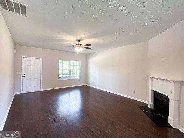 417 Bell Flower Trl, Locust Grove, GA 30248 - unfurnished living room with a fireplace with raised hearth, wood finished floors, visible vents, baseboards, and ceiling fan